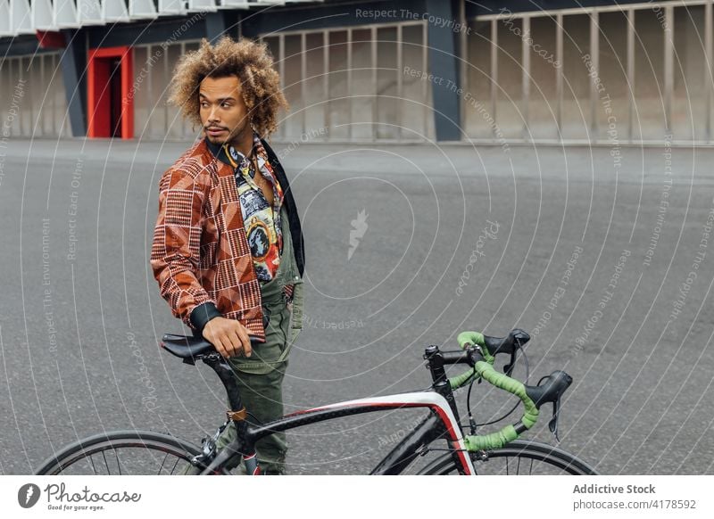 Ethnic man with bicycle standing on city street hipster urban young trendy bike commute informal traveler african american black ethnic lifestyle male