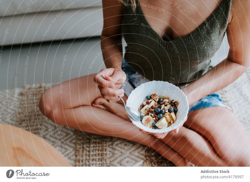 Anonymous woman having healthy breakfast at home healthy food granola eat detox muesli diet bowl female vitamin tasty sit morning meal fresh delicious floor