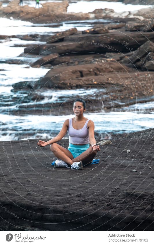 Relaxed woman doing yoga in Lotus pose on seashore lotus pose meditate beach padmasana mudra mindfulness zen female peaceful harmony practice healthy balance