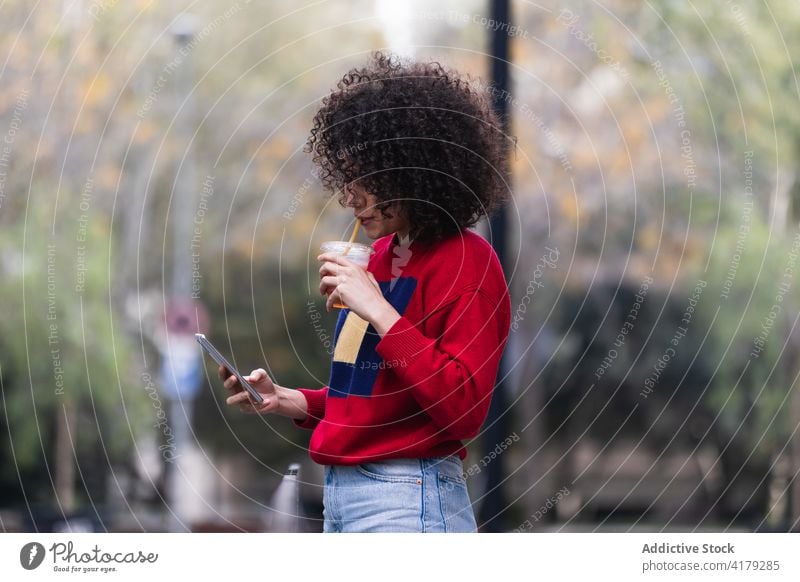 Black woman taking selfie with cup of takeaway juice smartphone take photo self portrait social media city enjoy female ethnic black african american outfit