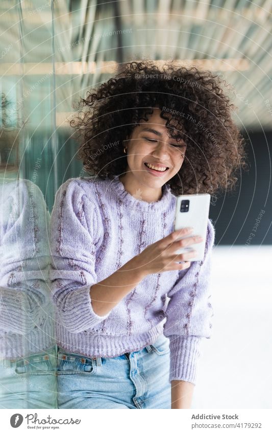 Black woman talking on mobile phone in city smartphone afro hairstyle phone call street urban female ethnic black african american hairdo curly hair modern