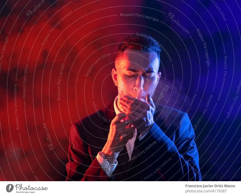 Elegant young man lighting a cigar on a black background. Selective focus copy space elegant caucasian model guy serious manager expression illuminated mature