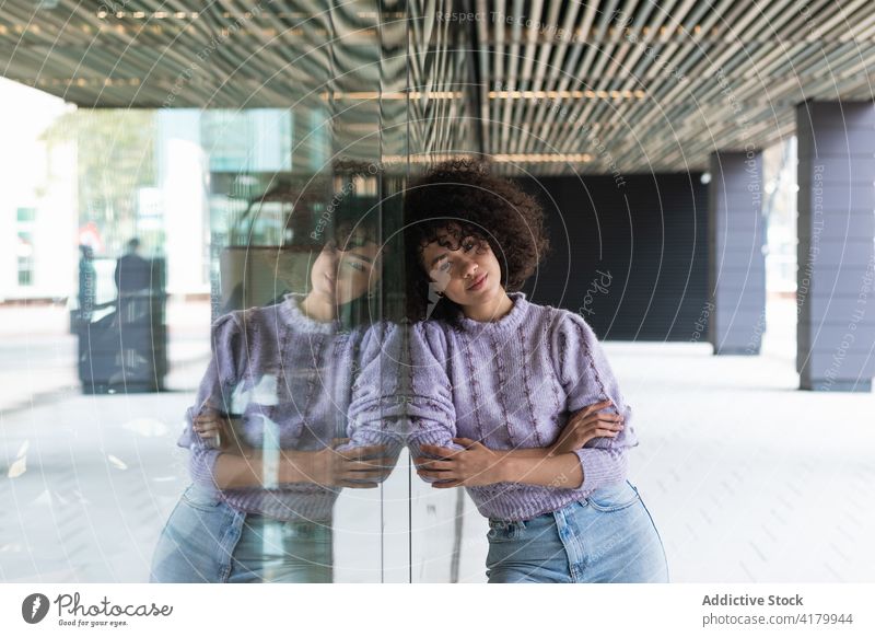 Dreamy black woman leaning on building on street thoughtful dreamy city think ponder curly hair afro contemplate female ethnic african american glass