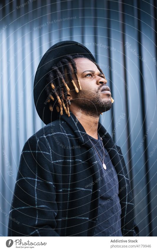 Brutal black guy in hat on street cool brutal street style man dreadlocks informal urban lifestyle confident rebel trendy appearance posture cityscape culture