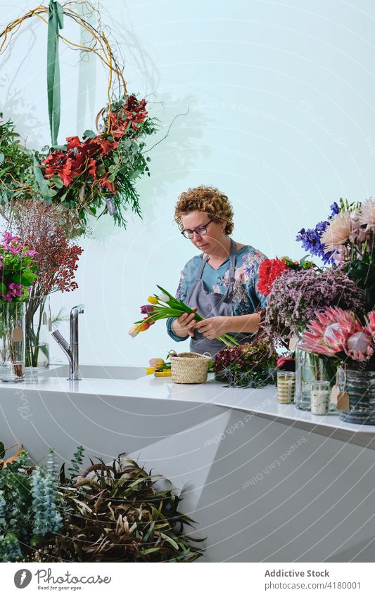 Florist creating floral bouquet in salon florist woman flower shop tulip bunch colorful fresh female calm bloom blossom apron occupation saleswoman retail