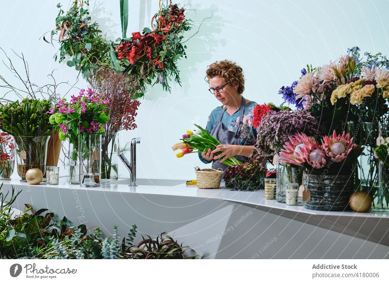 Florist creating floral bouquet in salon florist woman flower shop tulip bunch colorful fresh female calm bloom blossom apron occupation saleswoman retail