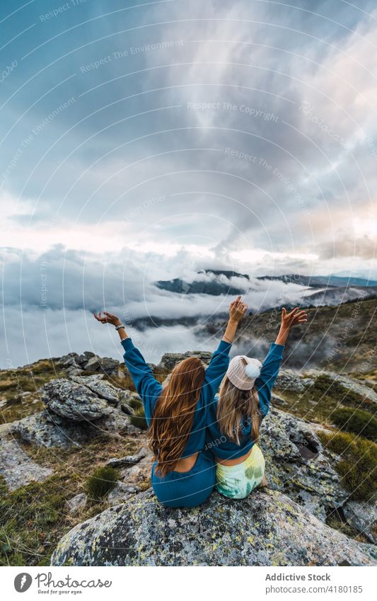 Carefree women on rock in mountains traveler together carefree freedom enjoy arms raised scenery vacation spectacular highland female nature tourism journey