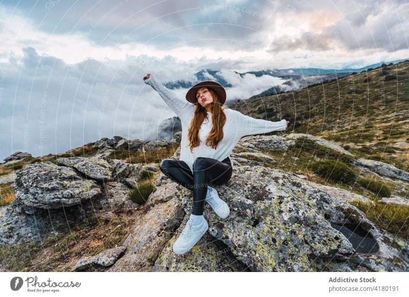 Woman in hat enjoying view of mountains woman observe viewpoint travel tourist highland admire explore female stone scenic sit nature traveler picturesque