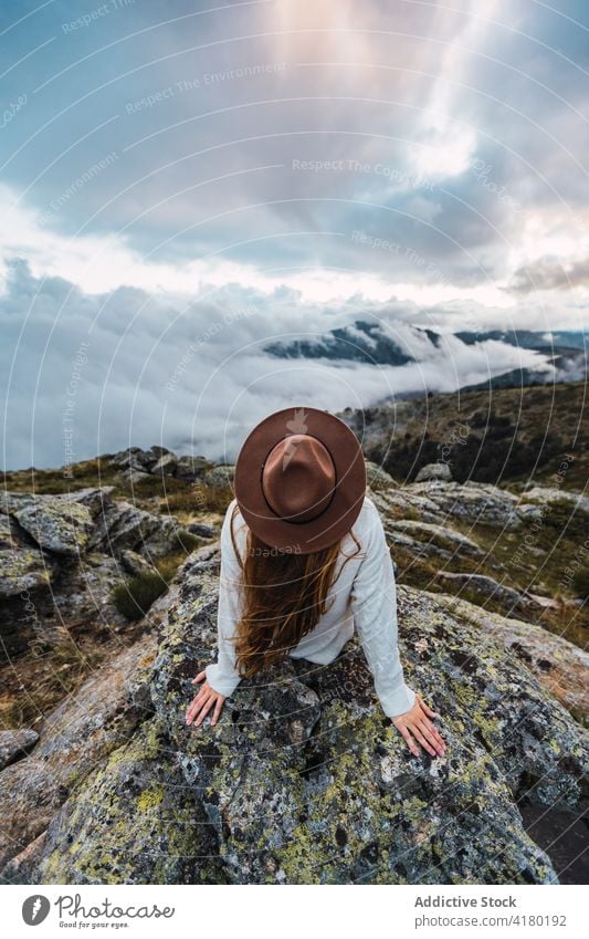 Woman in hat enjoying view of mountains woman observe viewpoint travel tourist highland admire explore female stone scenic sit nature traveler picturesque