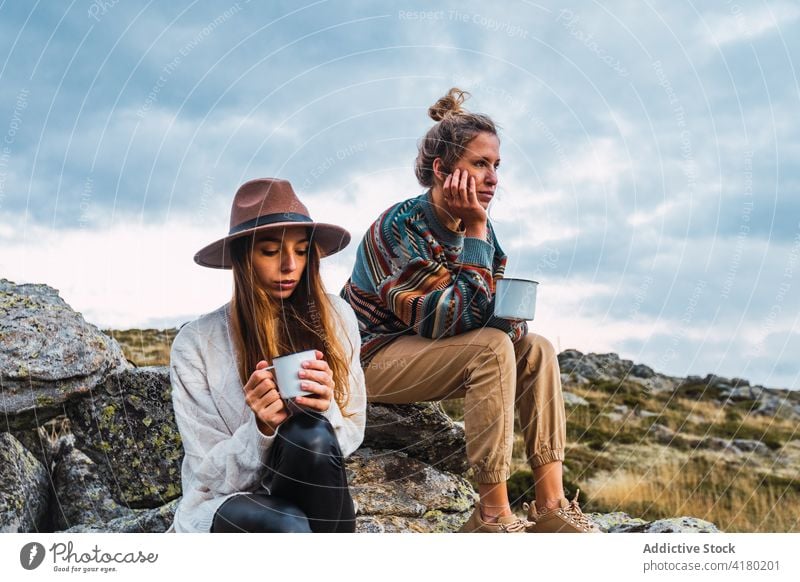 Women with hot beverage in cups in mountains traveler women hot drink highland relax carefree female landscape holiday trip adventure nature tourism friend