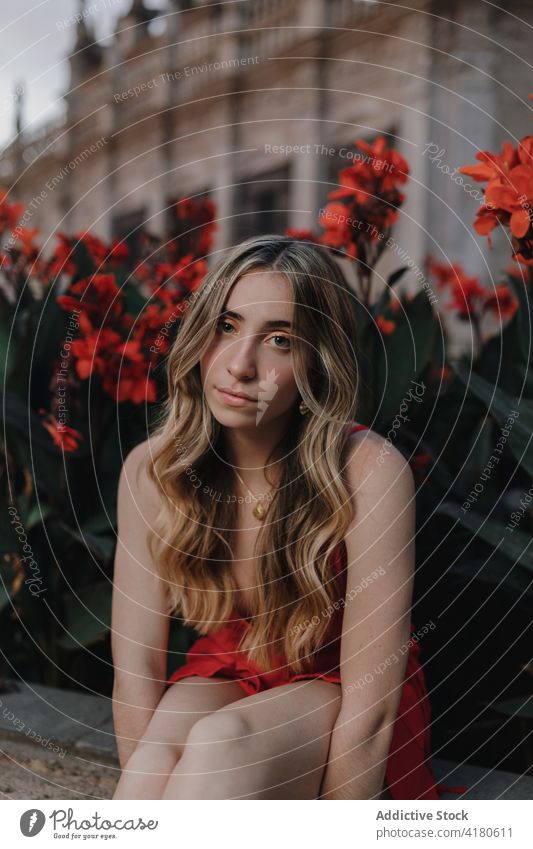 Dreamy woman looking at camera on flowerbed in town dreamy gentle mindfulness tender portrait bloom blossom makeup street romantic reflective eyeshadow cosmetic