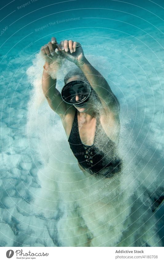 Woman in goggles swimming undersea and looking at camera woman underwater dive sand swimsuit diver female slim grace swimmer swimwear summer turquoise color