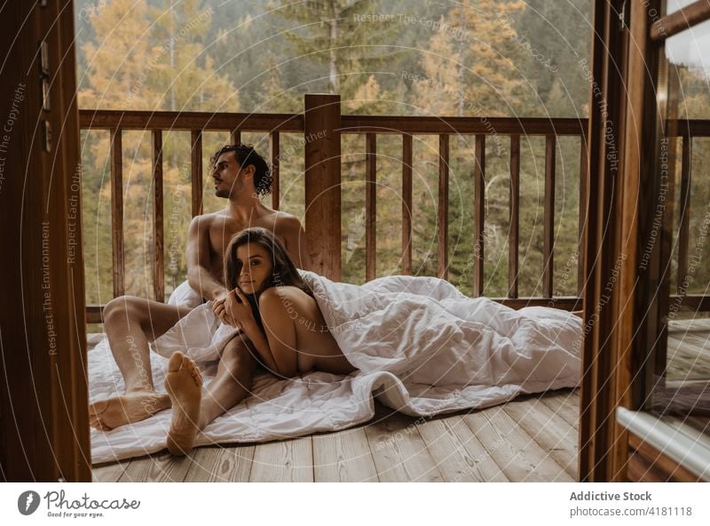 Serene naked couple lying on blanket on porch terrace cuddle autumn season bonding hug undress affection together romantic love serene peaceful cottage tender