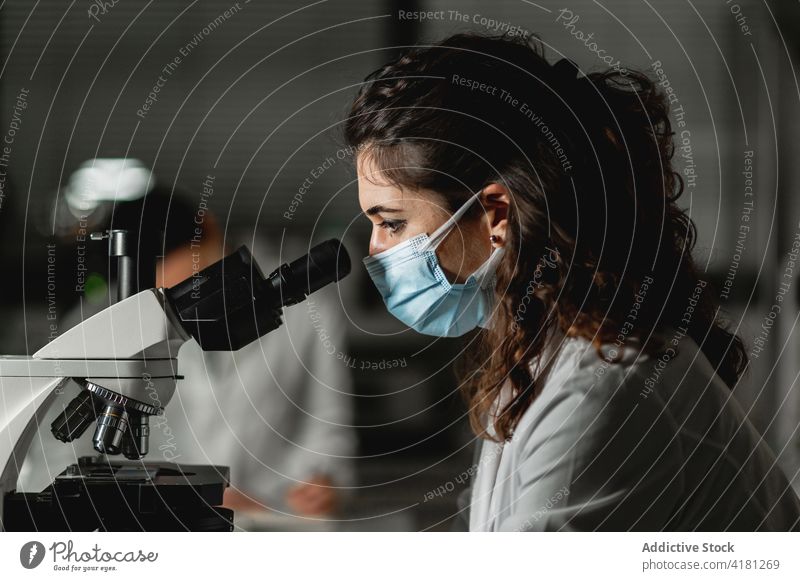 Scientist examining test samples through microscope scientist laboratory examine analyze equipment investigate using research experiment woman chemical modern