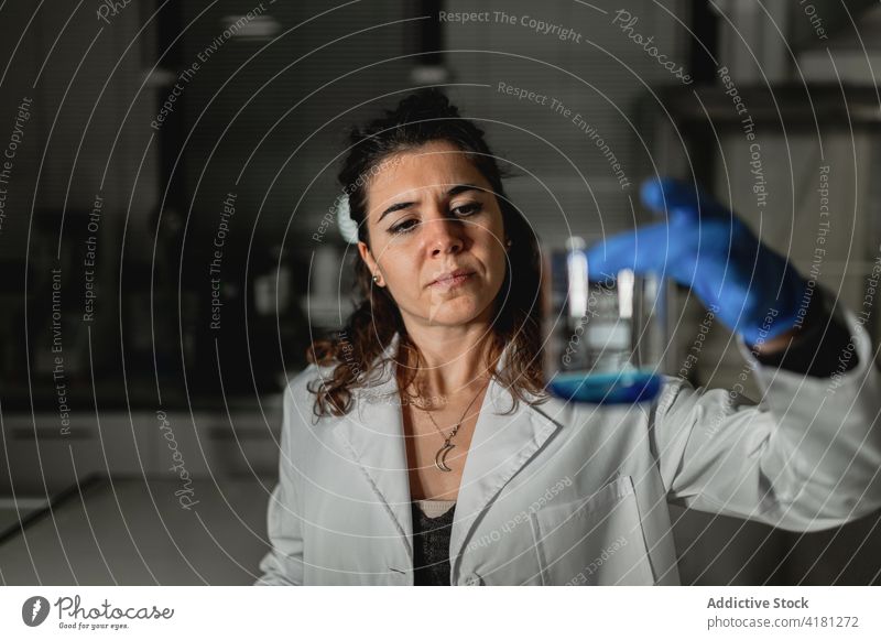 Focused scientist examining chemical solution in laboratory sterile liquid research chemistry examine glass pharmaceutical medicine experiment test biochemistry