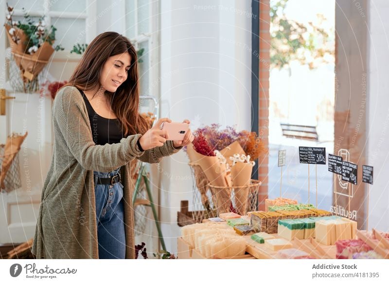 Positive woman taking picture of handmade soap shopper organic take photo smartphone price choice store female zero waste product device eco friendly bulk smile