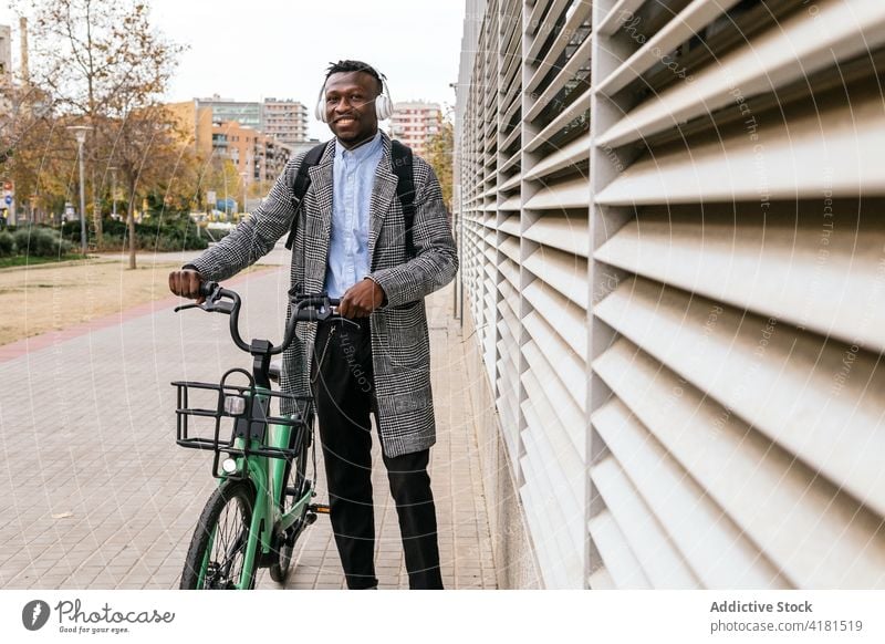 Cheerful black office worker with bicycle on city street man cheerful formal style vehicle pavement friendly town african american wall ribbed ethnic smile