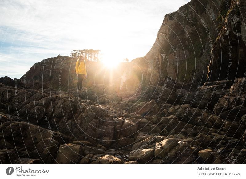 Unrecognizable traveler standing on rocky formation in sunlight woman explore mountain cliff slope highland sunbeam wanderlust nature asturias spain adventure