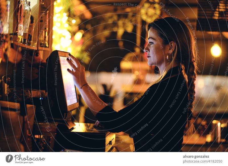 a beautiful young woman at the desk in a restaurant standing touching female cash register pay manage bar lifestyle touchscreen using bill business management