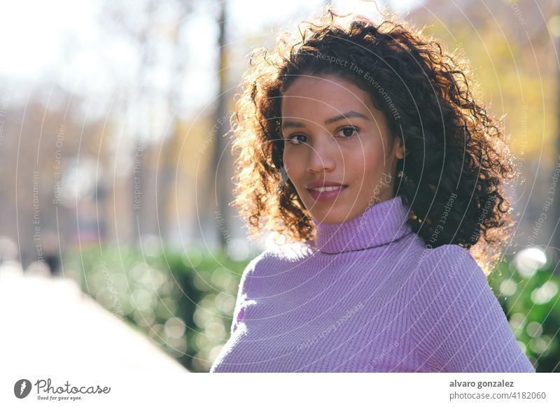 Young woman standing outdoors on the street. young urban sombrero style city closeup curly hair hairstyle clothing trendy one posing confident casual lifestyle