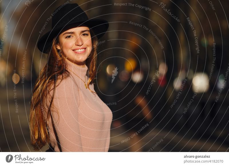 Woman smiling while standing outdoors. woman urban street sombrero city style young closeup sweater clothing outside one posing confident casual long hair