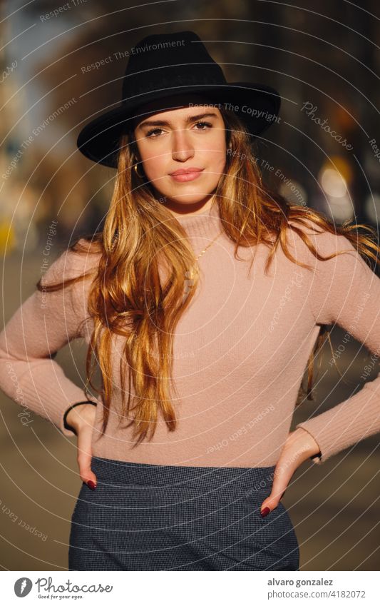 Woman standing outdoors on the street. young woman urban sombrero style city closeup t-shirt clothing outside one posing confident casual long hair looking