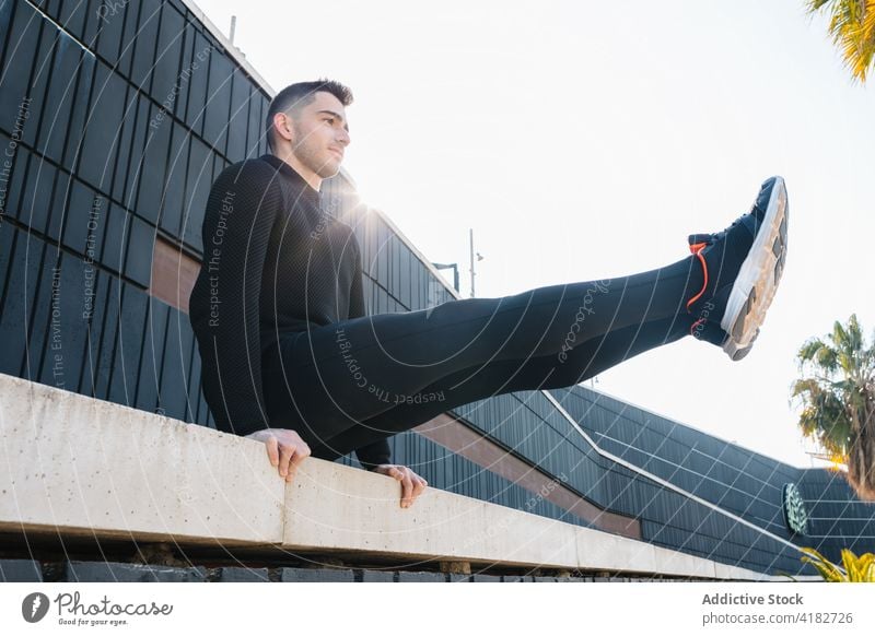 Young sportsman performing L sit on street railing l sit exercise fit strong intense workout energy effort sporty motivation challenge fitness vitality physical