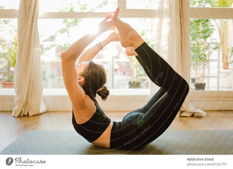 Flexible woman performing Bow pose on mat in house yoga bow pose flexible stretch practice eyes closed healthy lifestyle vitality mindfulness perfect barefoot