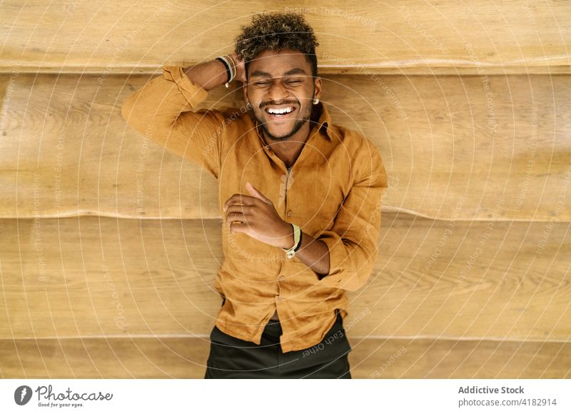 Smiling ethnic curly haired man looking at camera smile hipster beard young handsome cheerful happy stair male casual fence lifestyle black african american