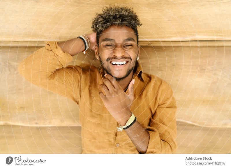 Smiling ethnic curly haired man looking at camera smile hipster beard young handsome cheerful happy stair male casual fence lifestyle black african american