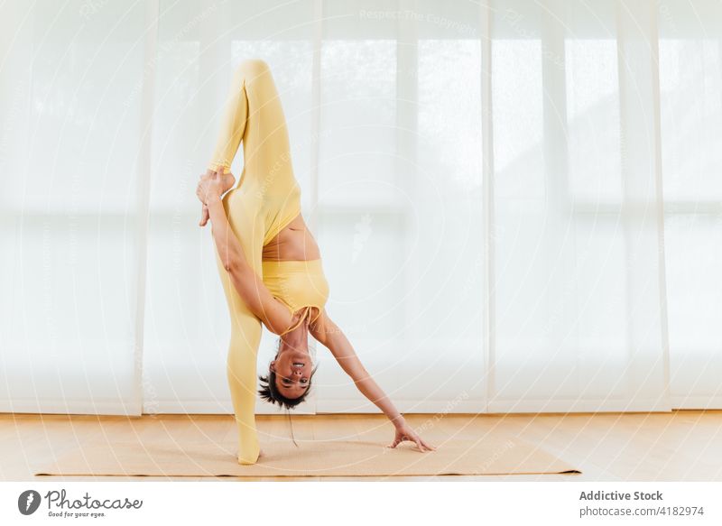 Flexible woman stretching body during yoga session bend posture exercise flexible grace female position focus arms raised uttanasana practice slender barefoot