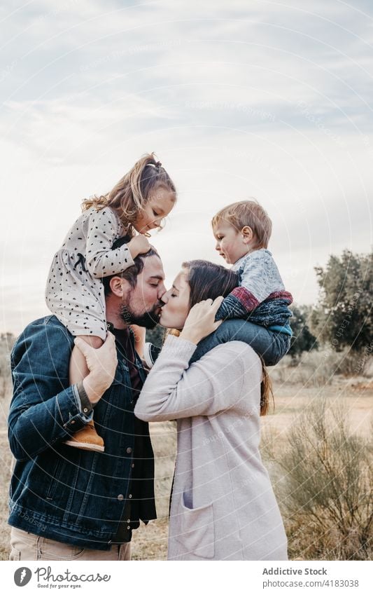 Happy family with children chilling in nature countryside couple kiss together enjoy weekend relationship love happy kid close father romantic soulmate relax