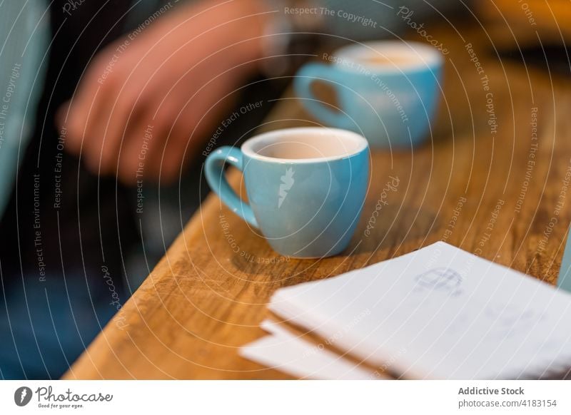 Crop barista at table with coffee cups espresso cafe counter notebook bartender small job work wooden beverage drink occupation coffee house coffee shop lean