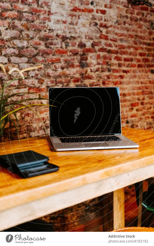 Laptop placed on counter in cafe laptop coffee shop coffee house netbook device loft style interior wooden table modern freelance workplace workspace design