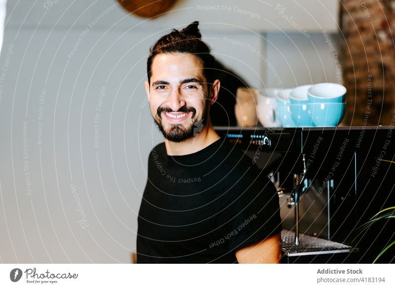 Cheerful barista preparing beverage in coffee machine prepare coffeemaker portafilter cafe cheerful drink man male bartender work job coffee shop service