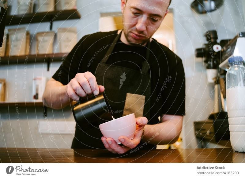 Close-up of a waiter serving milk to a cup of coffee service drink cafe cafeteria professional jug restaurant person espresso hot beverage man bar indoors male