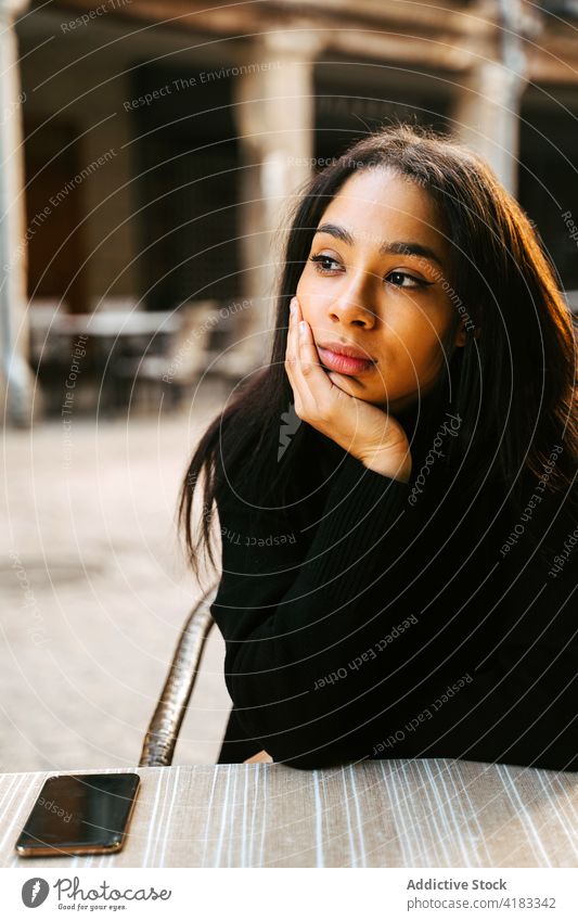 Dreamy ethnic female at street table woman dream cafe calm pensive urban town sidewalk casual wistful lifestyle relax thoughtful modern contemplate contemporary