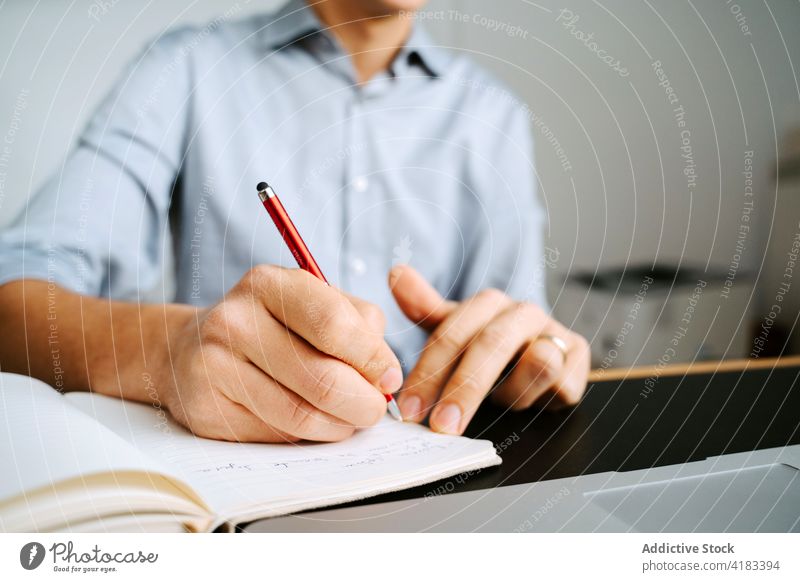 Crop businessman taking notes in notepad take note notebook plan organizer write memo entrepreneur project male table pen professional planner work career