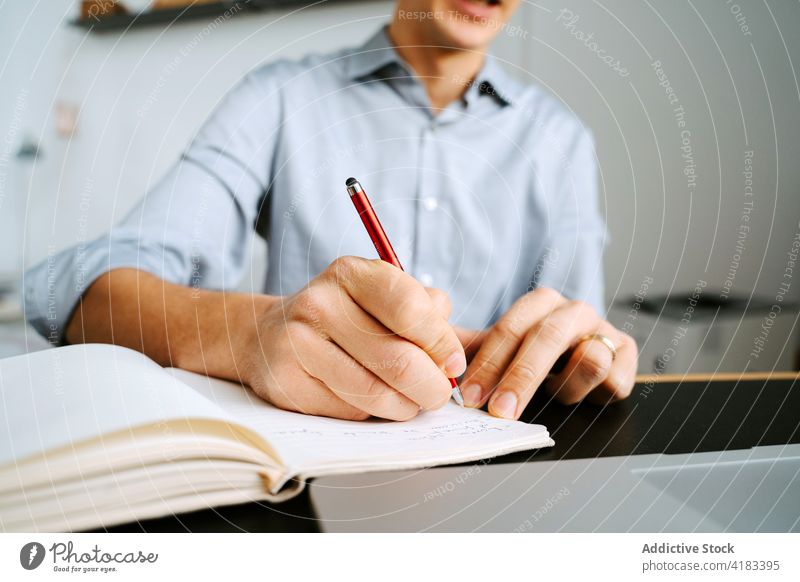 Crop businessman taking notes in notepad take note notebook plan organizer write memo entrepreneur project male table pen professional planner work career