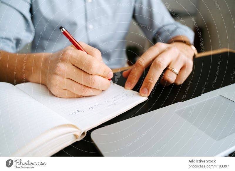 Crop businessman taking notes in notepad take note notebook plan organizer write memo entrepreneur project male table pen professional planner work career