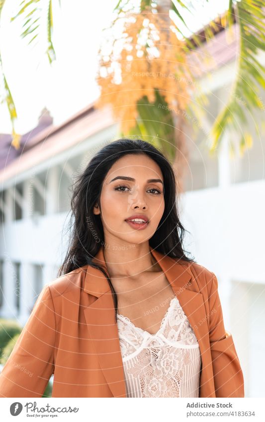 Confident ethnic woman in stylish outfit looking at camera style confident elegant self assured trendy smile brunette tropical female model fashion young