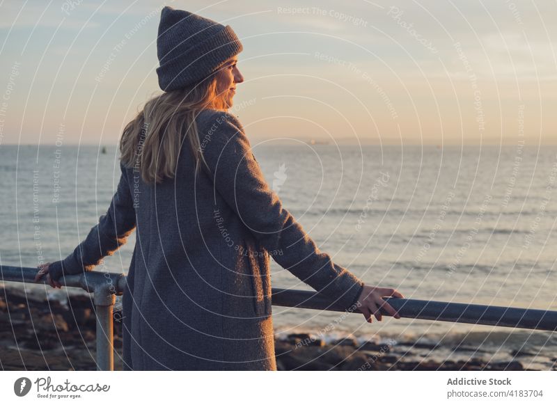 Happy woman enjoying sunset at seaside autumn admire happy smile shore young female evening lifestyle sundown relax rest ocean coast season travel nature