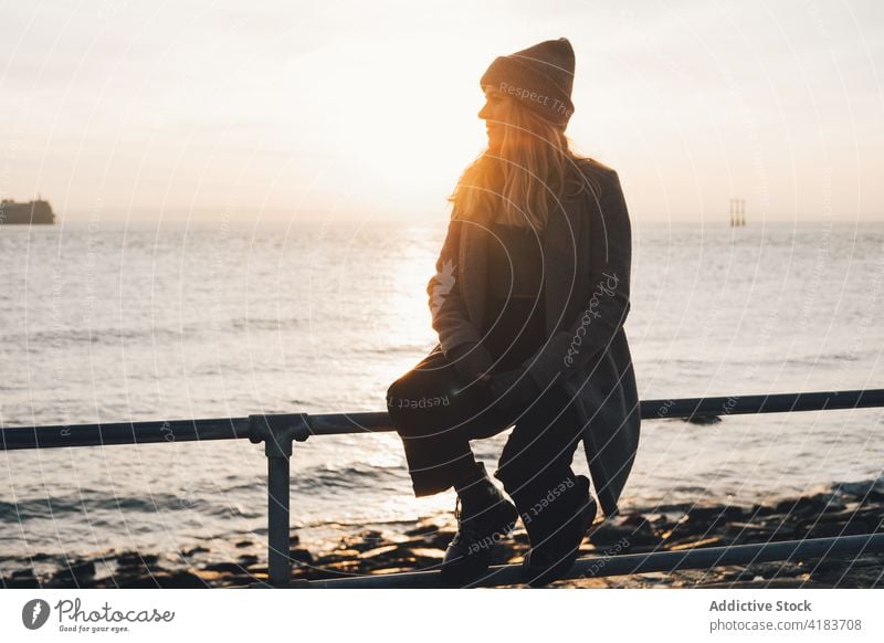 Happy woman enjoying sunset at seaside autumn admire happy smile shore young female evening lifestyle sundown relax rest ocean coast season travel nature