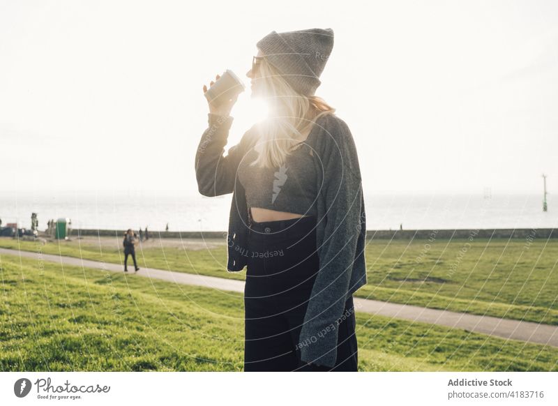 Woman drinking coffee near sea woman seaside rest traveler takeaway autumn relax young female lifestyle beverage enjoy nature to go vacation cup tourism