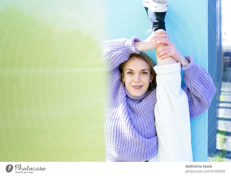 Fit woman doing standing split near concrete wall flexible leg raised fit content grace sporty stretch gymnastic neighborhood posture cheerful optimist young