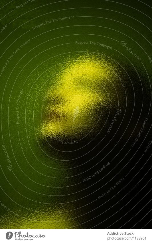 Unrecognizable person looking through blurred glass dark room melancholy mood shadow emotionless dim solitude shade unemotional light green color glow lonely