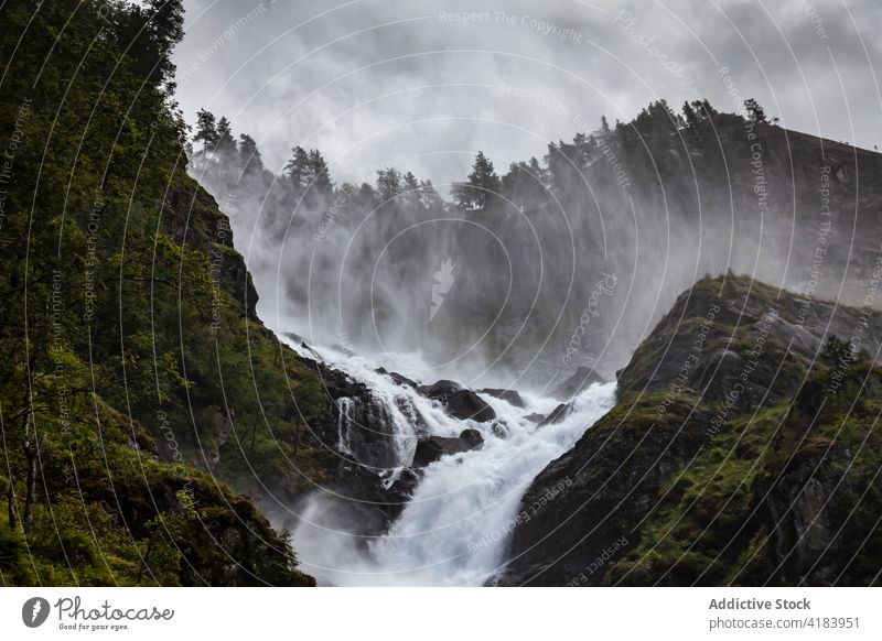 Fast mountain river flowing down rocky terrain rapid power landscape stream rough highland norway sky stone water spectacular cloudy scenery picturesque nature