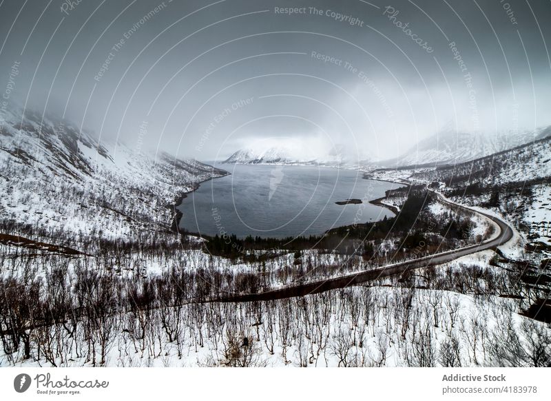 Road in snowy mountains near lake in winter road landscape endless roadway scenery majestic norway cloudy sky cold scenic breathtaking picturesque nature