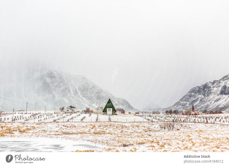 Lonely house near graveyard in mountainous valley wooden cemetery winter snow gravestone scenery norway highland quiet cabin cold nature calm landscape silent