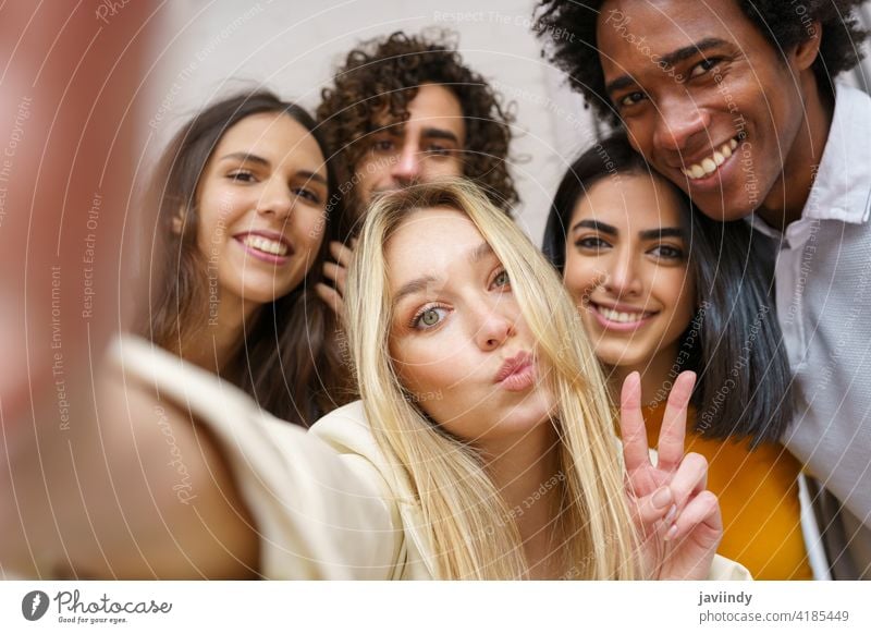 Multi-ethnic group of friends taking a selfie together while having fun outdoors. people smartphone multiracial multi-ethnic caucasian photographing students